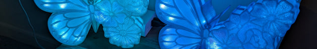 Two blue butterfly-shaped lights on a wooden surface in a dark setting.