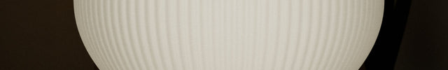 Table lamp with ribbed white shade and blue base on a wooden surface
