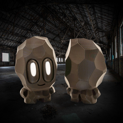 Two large stone-like sculptures with facial features in a dark, abandoned building.