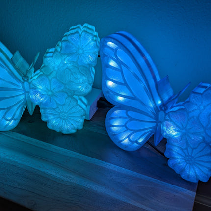 Two blue butterfly-shaped lights on a wooden surface in a dark setting.