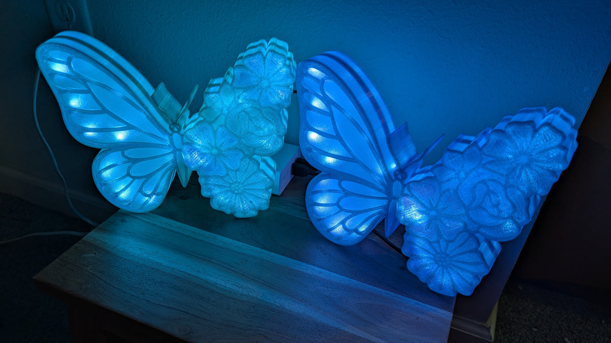 Two blue butterfly-shaped lights on a wooden surface in a dark setting.
